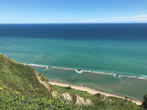 Paisatge costaner amb un bascul protector rocos, una platja sorrenca i vegetació exuberant.