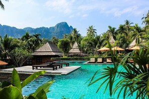 A resort pool with lounge chairs, palm trees, and a mountain backdrop. - Listing With Bookings, Messages abc (Pattaya)