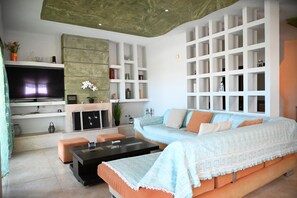 A modern living room with a sectional sofa, a flat-screen TV, a fireplace, and built-in shelving. - ✨ Erato Superior Suite: Your Modern Oasis 🏛️ (Κρεμαστή)