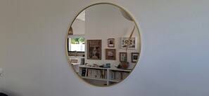 Ein Zimmer mit einem großen, ovalen Spiegel, einem Bücherregal und gerahmten Kunstwerken an der Wand.