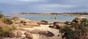 Un paysage côtier caractérisé par de gros rochers, une plage de sable et une eau calme.