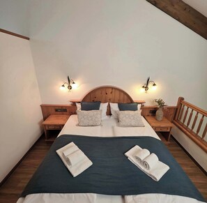 A bedroom with a wooden headboard, two bedside tables, a nightstand, and a wooden railing.