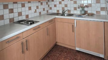 Eine Küche mit Holzausstattung, einem Spülbecken und einer gefliesten Spritzschutzwand.