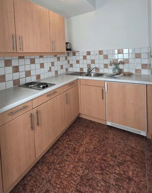 A kitchen with wooden cabinets, a sink, and a tiled backsplash.