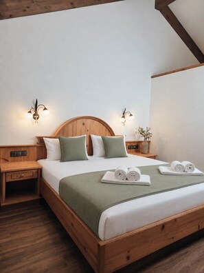 Ein ordentlich bezogenes Bett mit einem hölzernen Kopfteil, zwei Nachttischen und Wandleuchten.