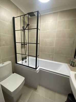 Une salle de bain avec une douche Ă parois de verre, des toilettes et une baignoire.