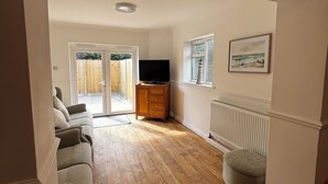 Ein Wohnzimmer mit Sofa, Fernseher, Holzschrank und Heizkörper.