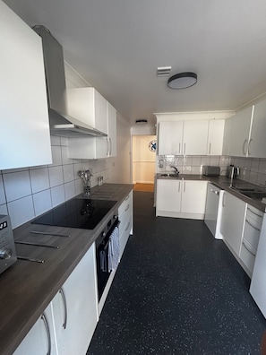 A modern kitchen with white cabinets, a black countertop, and a stainless steel range hood.