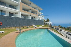 Ein modernes Hotel mit Swimmingpool, mehreren Balkonen und Meerblick.