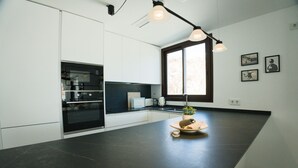 Cozinha moderna com bancada escura, forno embutido e janela com vista.