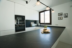 Eine moderne Küche mit dunkler Arbeitsplatte, integriertem Backofen und einem Fenster mit Aussicht.