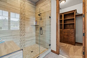 Une salle de bain moderne dotĂ©e dâune douche Ă parois de verre, dâun meuble-lavabo en bois et dâun placard intĂ©grĂ© avec de nombreux tiroirs.