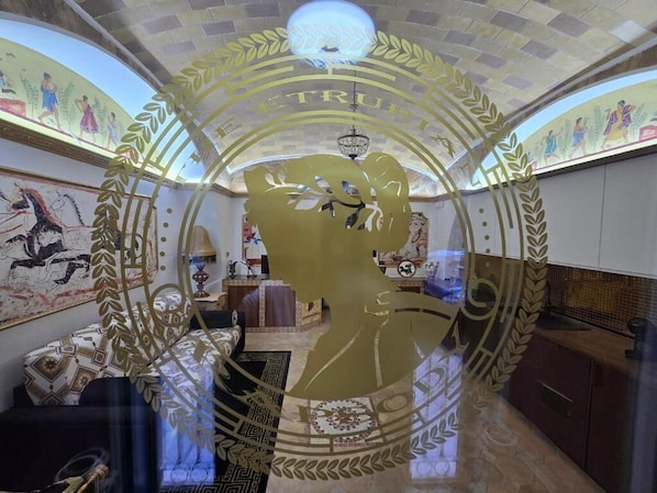 A room with a mural, a chandelier, and a decorative archway. - THE ETRURIAN RAPSODY (Roma)