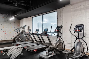 A gym with treadmills, elliptical machines, and a climbing wall.