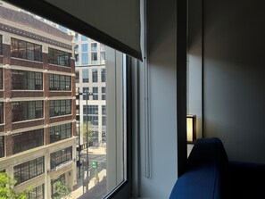 A room with a large window, a blue chair, and a lamp.