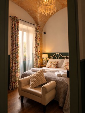A bedroom with a bed, a chair, a lamp, and a window with curtains.
