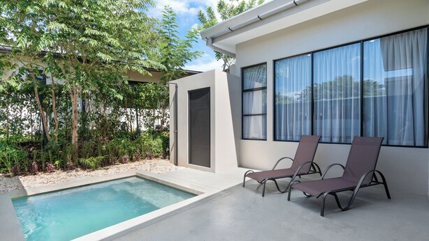 A modern outdoor pool area with two lounge chairs, a small pool, and a building with large windows. - Side by Side Villas Walking Distance to Both Playa Tamarindo & Playa Langosta (Playa Langosta)