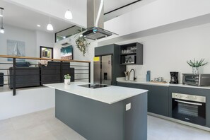 Eine moderne Küche mit Kochinsel, integrierten Geräten und Blick ins Freie.