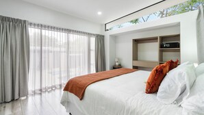 Camera d'albergo moderna con un letto grande, un comodino, televisione integrata e una finestra con tende.