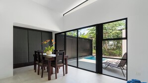Un interno moderno con zona pranzo, piscina e porta scorrevole in vetro che dà su uno spazio esterno.