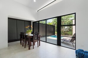 Ein modernes Interieur mit Essbereich, Pool und einer Schiebeglastür zu einem Außenbereich.