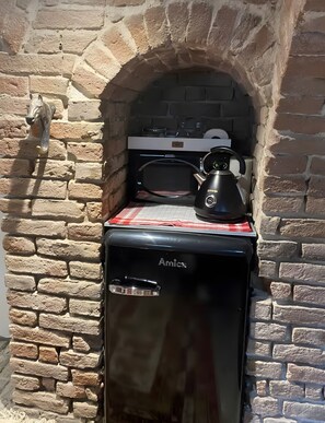 Ein Backofen aus Ziegelsteinen mit einem schwarzen Gerät und einem Wasserkocher darauf.