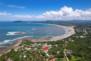 An aerial view of a coastal town with a beach, houses, and a red location marker. - Brand New 3 Bedroom Villa, Walking Distance to Tamarindo and Langosta (Playa Langosta)