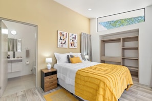 A bedroom with a bed, bedside tables, a wardrobe, and a bathroom visible through an open door. - Brand New 3 Bedroom Villa, Walking Distance to Tamarindo and Langosta (Playa Langosta)