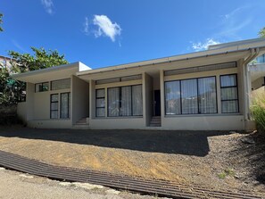 A modern two-story house with large windows, a flat roof, and a gravel driveway. - Brand New 3 Bedroom Villa, Walking Distance to Tamarindo and Langosta (Playa Langosta)