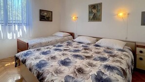 A bedroom with two single beds, a large bed with a floral bedspread, a hanging light fixture, and two wall-mounted lamps. - 2 Bedroom Apartment Bor in Poljana (Preko)
