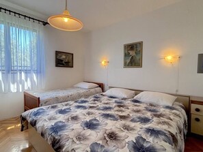 Ein Schlafzimmer mit zwei Einzelbetten, einem großen Bett mit floralem Überwurf, einer Hängelampe und zwei Wandleuchten.
