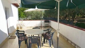 An outdoor patio with a round table, four chairs, a large umbrella, and a metal pole. - 2 Bedroom Apartment Bor in Poljana (Preko)