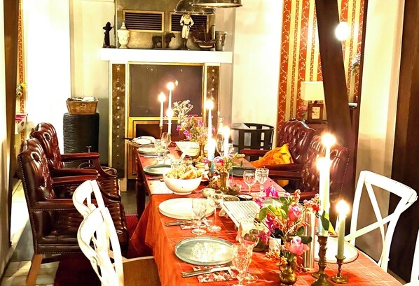 Ein Essbereich mit einem langen Tisch, gedeckt für eine Mahlzeit, umgeben von Stühlen und dekoriert mit Blumen und Kerzen.