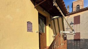 A building with a wooden staircase, a door, and a small balcony with a railing.