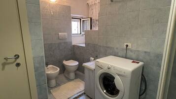 Une petite salle de bain comprenant des toilettes, un bidet et un lave-linge.