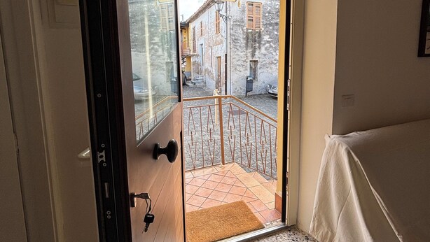 An open door leading to a balcony with a tiled floor and a view of a street.