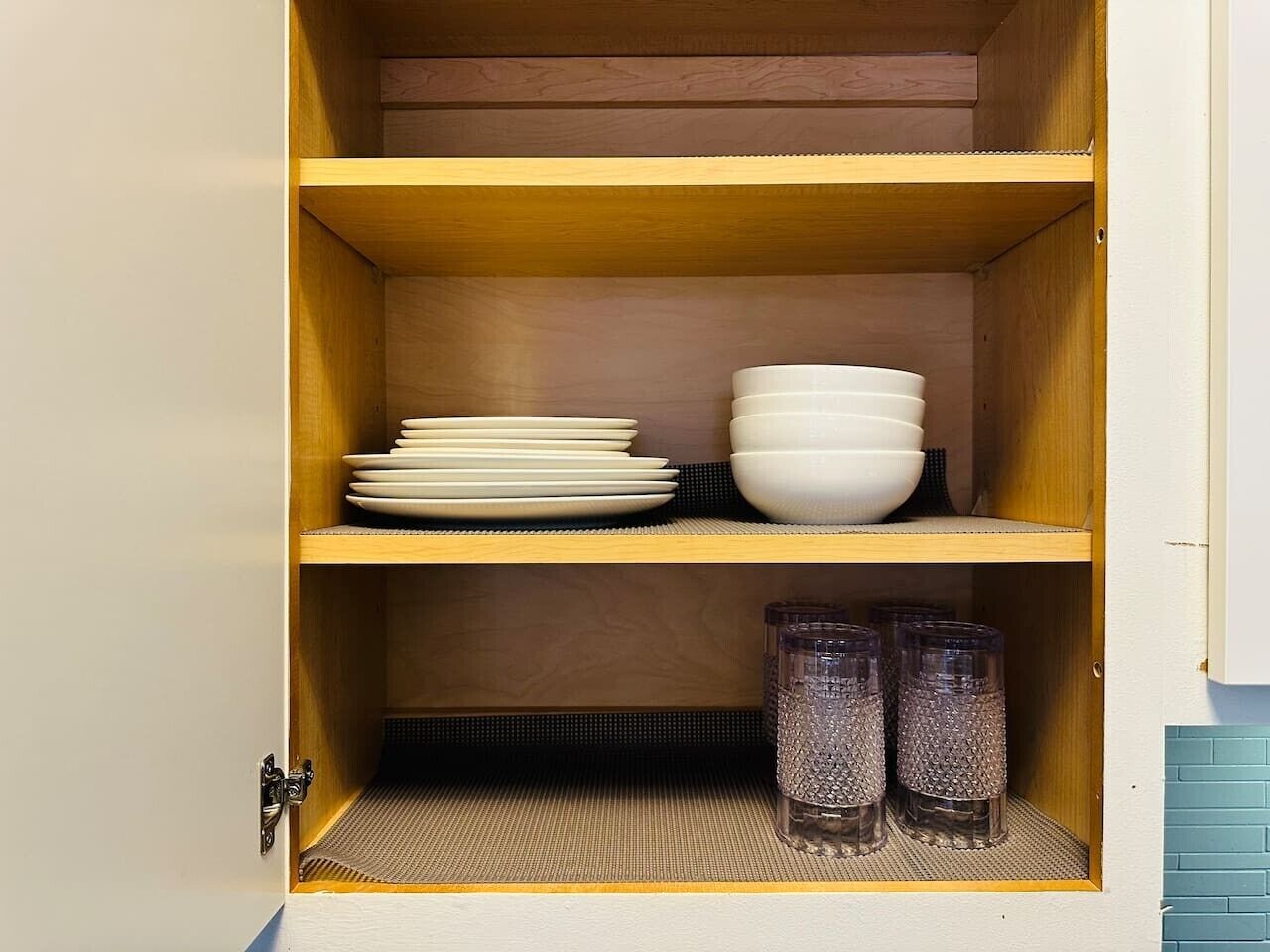 A wooden cabinet with shelves containing stacked plates, bowls, and glass jars.