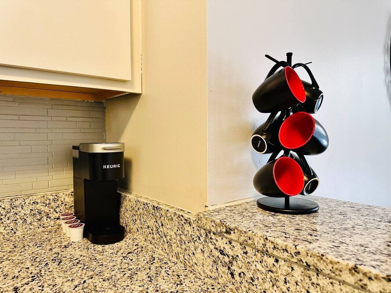 A coffee maker and a mug holder on a granite countertop.