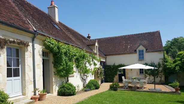 A two-story house with a garden, a patio with outdoor furniture, and a white umbrella. - Large, cosy family home with swimming pool in the heart of the Perche region. (Perche en Nocé)