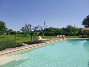A swimming pool with lounge chairs and a shaded area. - Large, cosy family home with swimming pool in the heart of the Perche region. (Perche en Nocé)