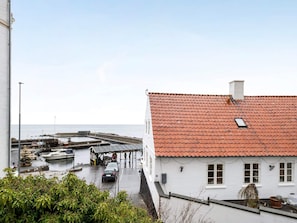 Ein Küstenhaus mit rotem Ziegeldach, einer überdachten Anlegestelle und Blick aufs Meer.