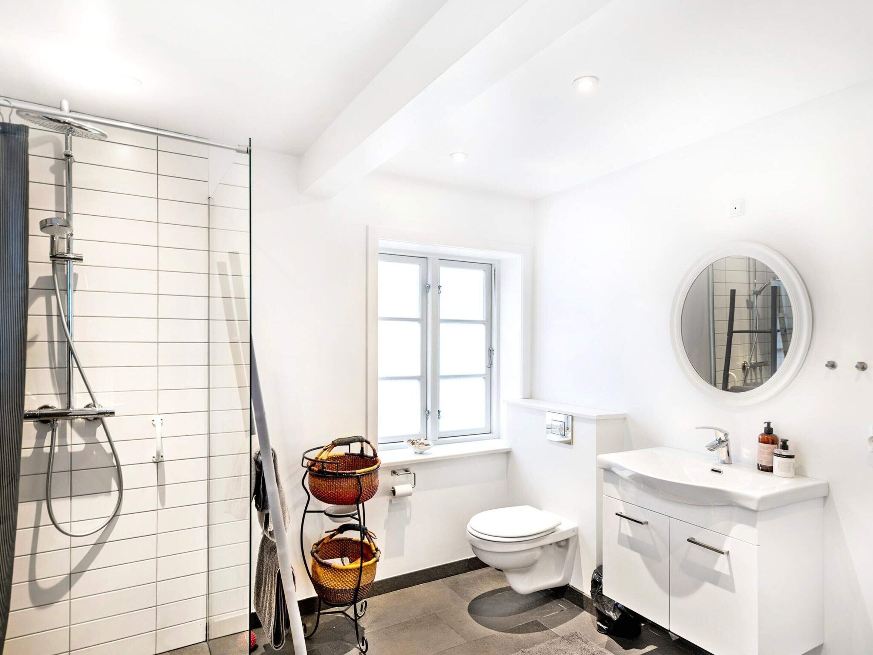A modern bathroom with a shower, toilet, and sink.