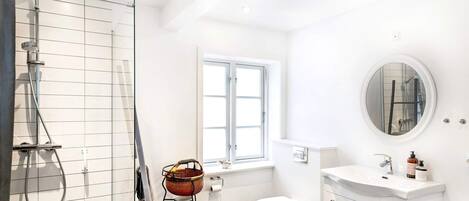 A modern bathroom with a shower, toilet, and sink.