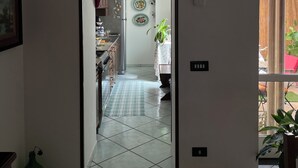 A hallway leading to a kitchen with a tiled floor, a hanging light fixture, and a framed picture on the wall. - CasaElia | Path of the Gods & Amalfi Coast (Pianillo)