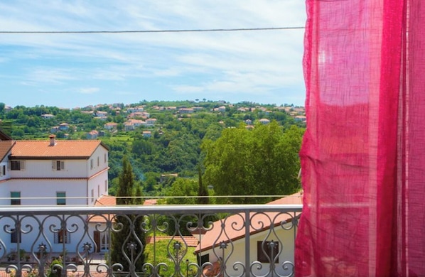 A balcony with a wrought iron railing overlooking a residential area with houses and greenery. - CasaElia | Path of the Gods & Amalfi Coast (Pianillo)