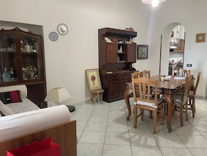 A dining area with a wooden table and chairs, a cabinet with decorative items, and a mirror reflecting the room. - CasaElia | Path of the Gods & Amalfi Coast (Pianillo)