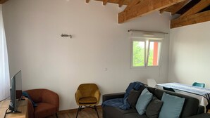 Una sala de estar con un sofá, un sillón, un televisor y una ventana.