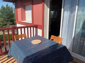 Ein Balkon mit Tisch und Stühlen, einem roten Geländer und einer Schiebetür.