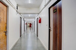 A long, narrow hallway with doors on both sides, a fire extinguisher mounted on the wall, and a door labeled '101' on the right.