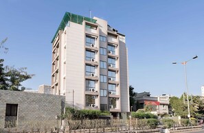 A multi-story building with a flat facade, air conditioning units, and a street lamp. - Deluxe Aura Inn (Ahmedabad)